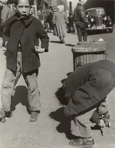 105th Street - Two boys playing with roller skates, each wearing a single roller..., 1947 - 1951. Creator: Romulo Lachatanere