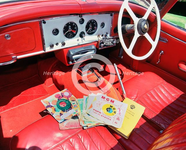 1960 Jaguar XK150 interior with record player and 7inch vinyl discs.. Creator: Unknown.