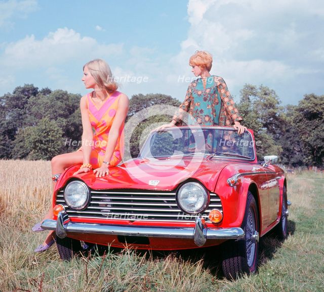 1968 Triumph TR5 with female models, (copyright B.M.I.H.T.). Creator: Unknown.