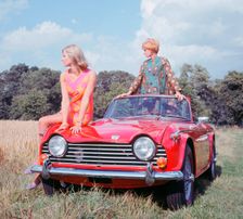 1968 Triumph TR5 with female models, (copyright B.M.I.H.T.). Creator: Unknown