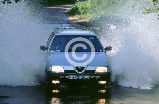 1989 Alfa Romeo 164 driving through a ford. Artist: Unknown.