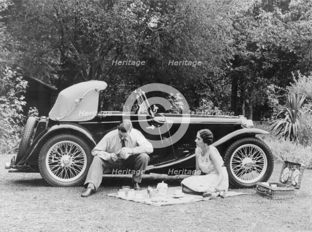 Couple having a picnic by an MG TA Midget, late 1930s. Artist: Unknown