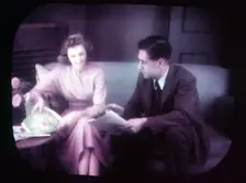 Couple sitting on sofa within TV screen, c1955. Creator: Arthur Charles Kirby Ware