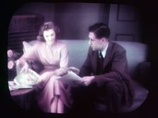 Couple sitting on sofa within TV screen, c1955. Creator: Arthur Charles Kirby Ware