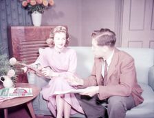Couple sitting on sofa, c1955. Creator: Arthur Charles Kirby Ware
