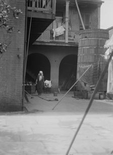 Courtyard with cistern and woman cleaning, New Orleans, between 1920 and 1926. Creator: Arnold Genthe