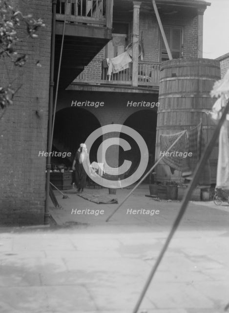 Courtyard with cistern and woman cleaning, New Orleans, between 1920 and 1926. Creator: Arnold Genthe.