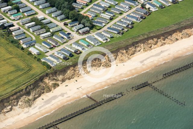 Coastal erosion between a caravan park and the sea defences at Corton Cliffs, Suffolk, 2019. Creator: Historic England.