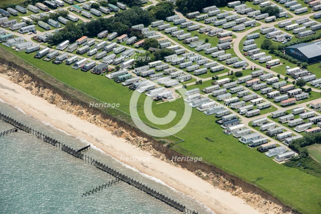 Coastal erosion between a caravan park and the sea defences at Corton Cliffs, Suffolk, 2019. Creator: Historic England.