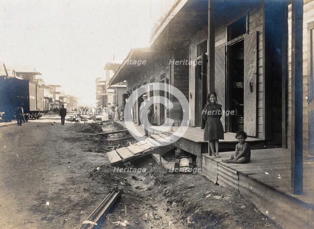 Colón, Panama: unpaved street lined with wooden houses; two children watch from a porch..., 1906. Creator: Unknown.