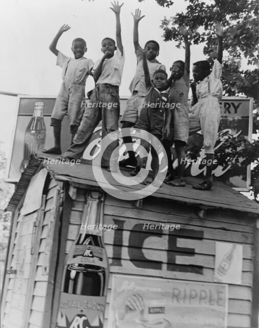 Colored boys playing on top of Coca Cola stand, Little Rock, Arkansas, 1938. Creator: Dorothea Lange.