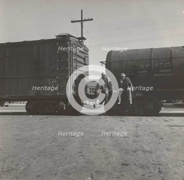 Colored itinerants on oil tank cars passing through Kingsbury, California, 1938. Creators: Farm Security Administration, Dorothea Lange.