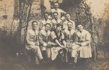 Concert party performers, one in drag, pose for a group portrait, (between 1910 and 1919?). Creator: Unknown
