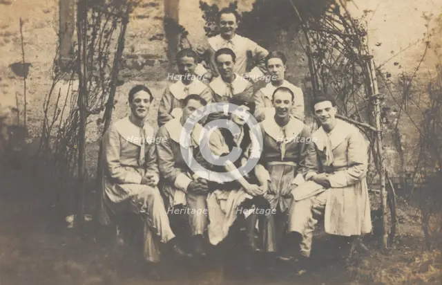 Concert party performers, one in drag, pose for a group portrait, (between 1910 and 1919?). Creator: Unknown.