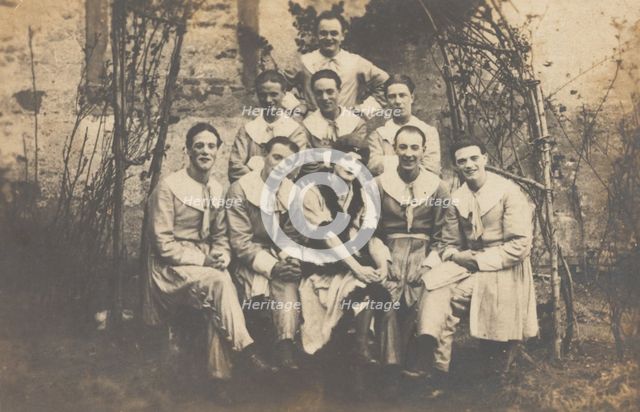 Concert party performers, one in drag, pose for a group portrait, (between 1910 and 1919?). Creator: Unknown.