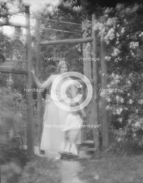 Conroy, Frank, Mrs., and child, standing by a garden gate, 1923 Creator: Arnold Genthe.