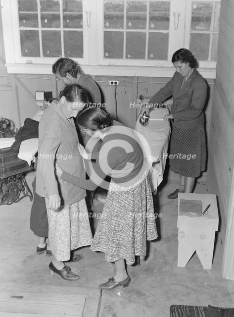 Camper receives help in fitting a coat from WPA sewing instructor, FSA, California, 1938. Creator: Dorothea Lange.