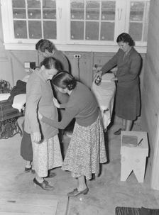 Camper receives help in fitting a coat from WPA sewing instructor, FSA, California, 1938. Creator: Dorothea Lange
