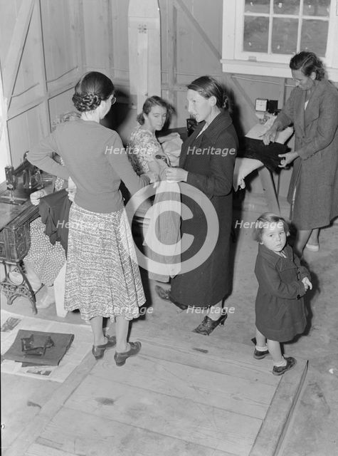 Camper receives help in fitting a coat from WPA sewing instructor, FSA, California, 1938. Creator: Dorothea Lange.