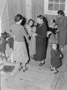 Camper receives help in fitting a coat from WPA sewing instructor, FSA, California, 1938. Creator: Dorothea Lange