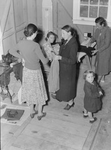 Camper receives help in fitting a coat from WPA sewing instructor, FSA, California, 1938. Creator: Dorothea Lange