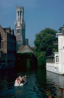 Canal, old houses, and the Belfrey of the Tour Des Halles in Bruges