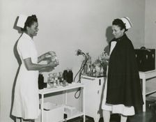 Captain Mary L. Petty, Chief Nurse, holding a glass bottle and showing it to 2nd Lieut..., 1939 - 19 Creator: Unknown