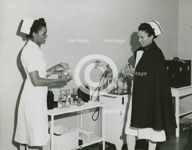 Captain Mary L. Petty, Chief Nurse, holding a glass bottle and showing it to 2nd Lieut..., 1939 - 19 Creator: Unknown.