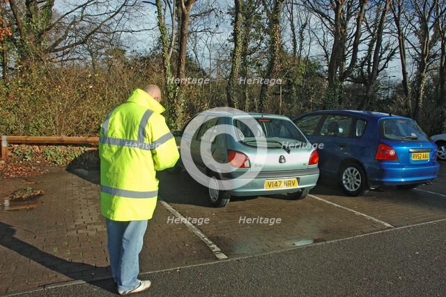 Car Park attendant recording car registration numbers. Artist: Unknown.