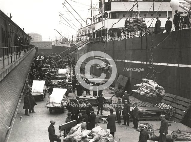 Cargo being loaded or unloaded from a ship, Royal Victoria Dock, Canning Town, London, c1930. Artist: Unknown