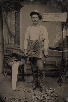 Carpenter or Cabinetmaker Standing Before a Sign Advertising His Trade, 1860s-80s. Creator: Unknown