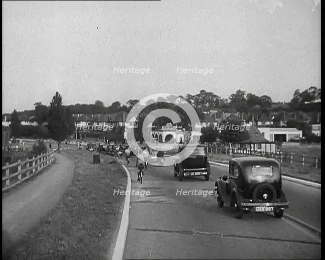 Cars and Bikes Driving Down a Road Away from the Camera, 1930s. Creator: British Pathe Ltd.