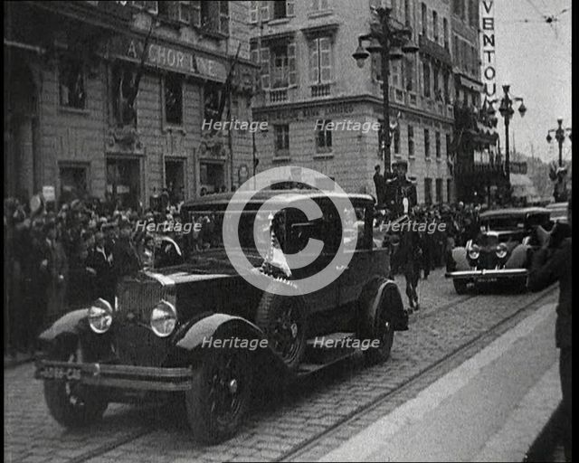 Cars Driving Down a Road, Watched by a Crowd, 1934. Creator: British Pathe Ltd.