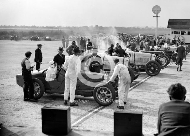 Cars on the start line, Surbiton Motor Club race meeting, Brooklands, Surrey, 1928. Artist: Bill Brunell.