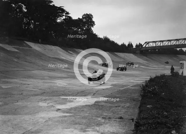 Cars racing on the Members Banking at a JCC Members Day, Brooklands. Artist: Bill Brunell.