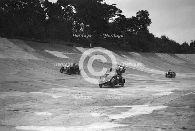 Cars racing on the banking at a JCC Members Day, Brooklands. Artist: Bill Brunell.