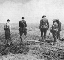 Chaplain conducting burial service in the field while burial party pay their respects, c1916