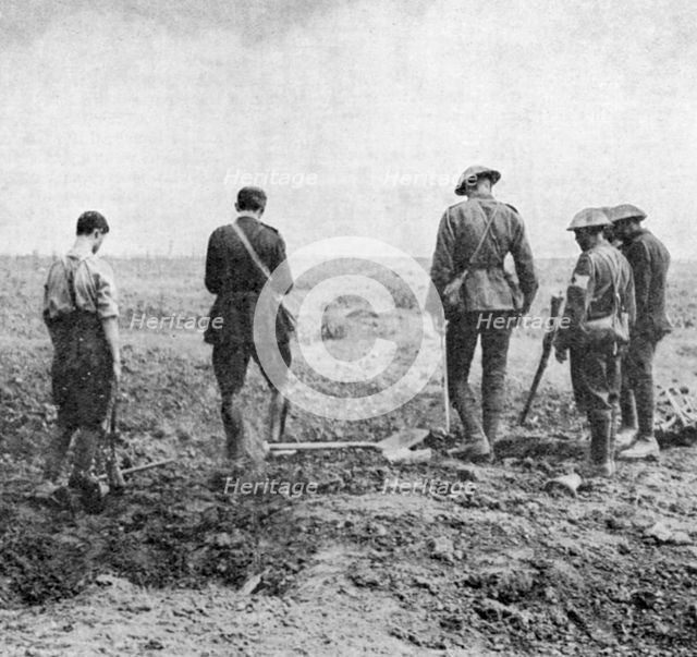 Chaplain conducting burial service in the field while burial party pay their respects, c1916. Artist: Unknown