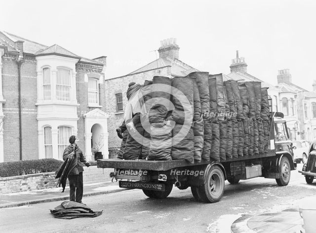 Charringtons delivering sacks of coal down a residential street. Creator: Unknown.