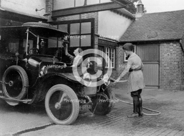 Chauffeuse washing car with hosepipe circa 1911. Creator: Unknown.