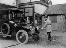 Chauffeuse washing car with hosepipe circa 1911. Creator: Unknown