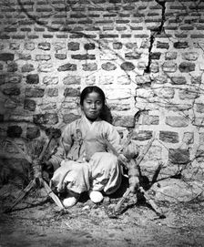 Child sitting by a wall, Korea, c1900