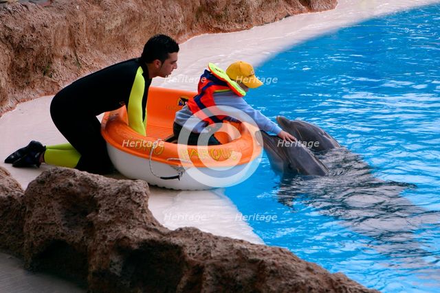 Child petting a dolphin, Loro Parque, Tenerife, Canary Islands, 2007.