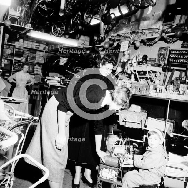 Child trying out a toy in a London toy store, c1950s. Artist: Henry Grant