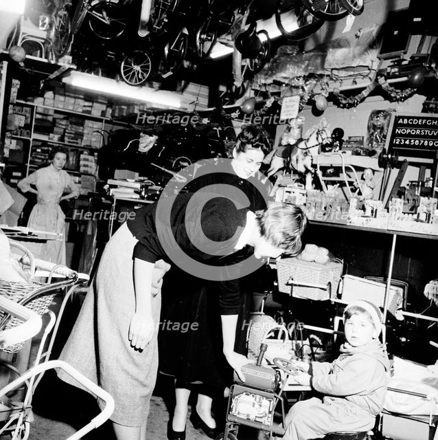 Child trying out a toy in a London toy store, c1950s. Creator: Henry Grant.