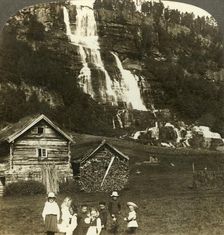 Children at play in a farmer's field with terraced Tvinde waterfall, Vossevangen, Norway c1905. Creator: Unknown