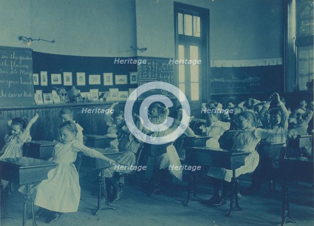 Children doing calisthenics while sitting at their desks in a classroom..., Washington, DC, (1899?). Creator: Frances Benjamin Johnston.