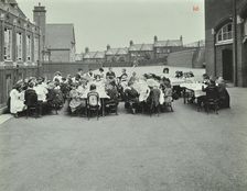 Children eating dinner at tables in the playground, Shrewsbury House Open Air School, London, 1908