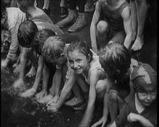 Children Splashing in Water in the Gutter During a Heatwave in New York City, 1921. Creator: British Pathe Ltd