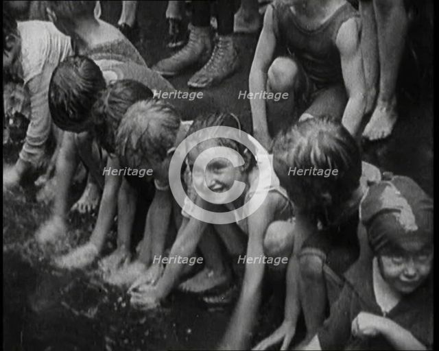 Children Splashing in Water in the Gutter During a Heatwave in New York City, 1921. Creator: British Pathe Ltd.
